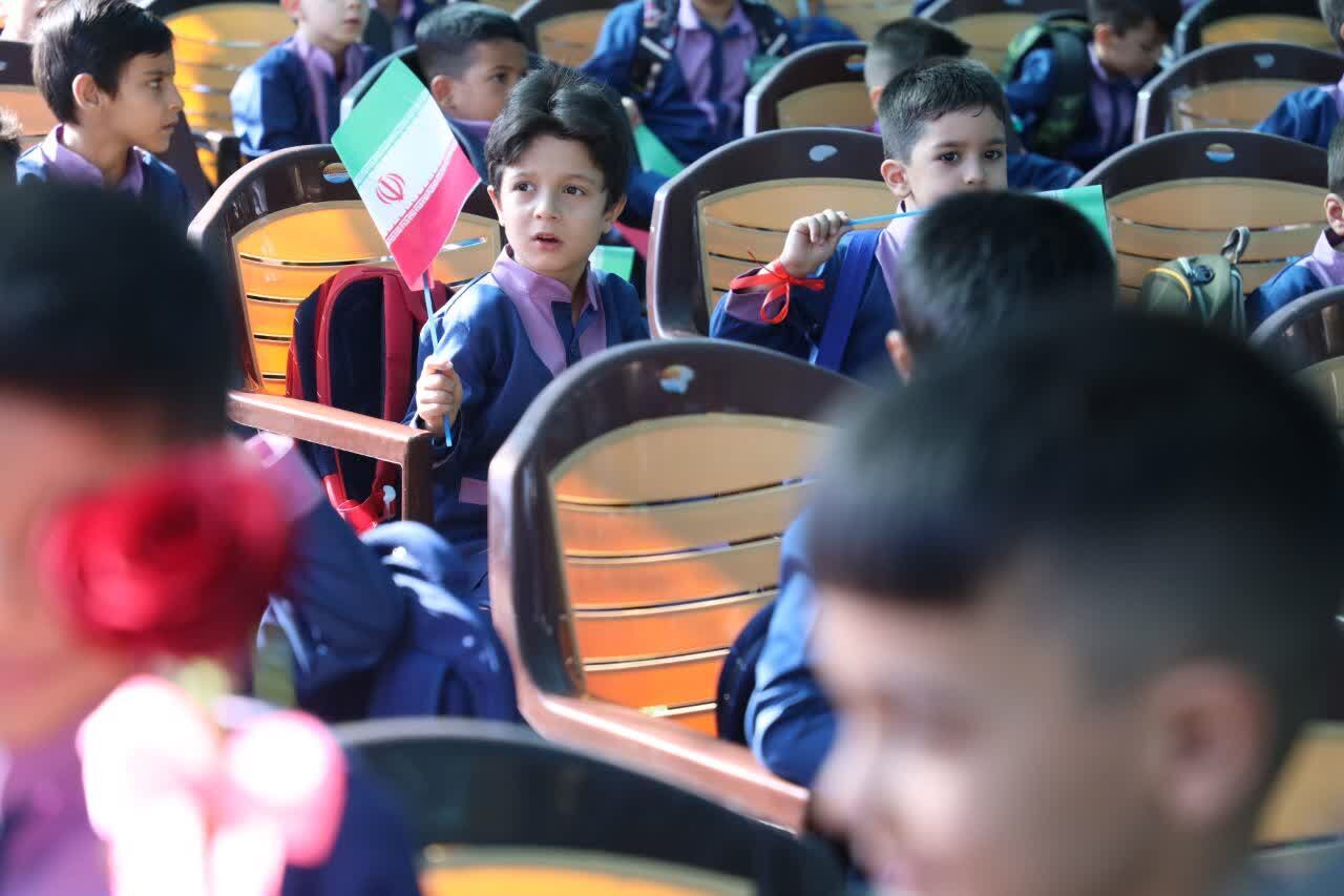 پرچم سه‌رنگ ایران در میان میدان مدرسه با لبخند کلاس اولی‌ها